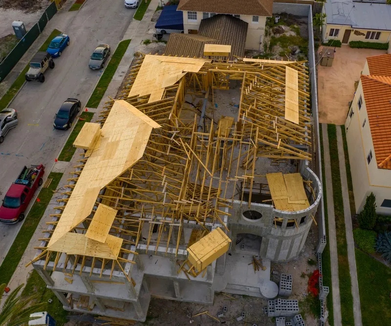 A home being built with roof rafters going up and a drone view looking down on it to do an insurance inspection